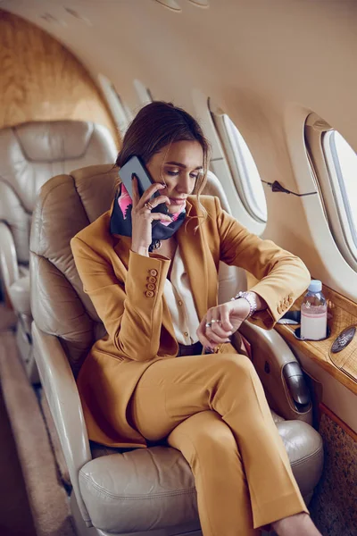 Деловая женщина разговаривает по мобильному телефону в самолете — стоковое фото