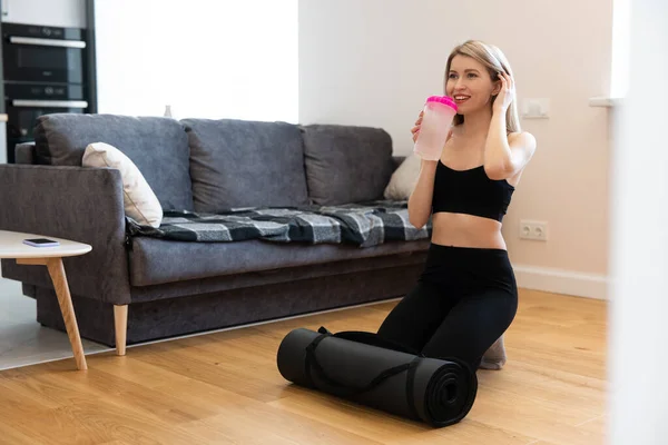 Deportiva bebiendo agua de la botella en casa — Foto de Stock