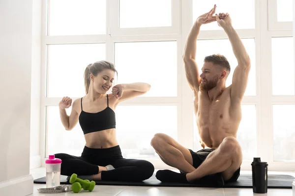 Sports couple sit and warm up on fitness mat — Stock Photo, Image