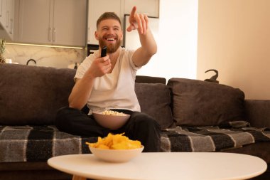 Gülen adam kanepede oturup televizyon ya da film izler.