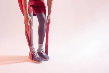 Sporcu adam direniş bandıyla egzersiz yapıyor.