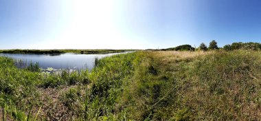 Nehrin kıvrımları çimenli çayır otlakları ve açık mavi gökyüzü