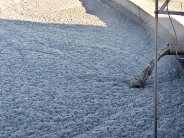Kanalizasyon borularından, biyolojik tedavi tesislerinin beton tankına atık su boşaltımı. Su yüzeyinde köpüklü kirli köpük.