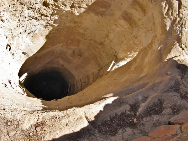 Çölde kurumuş su kuyusu. Kum taşının sarı dokusu ve ip merdiven. Yerde yuvarlak bir delik..