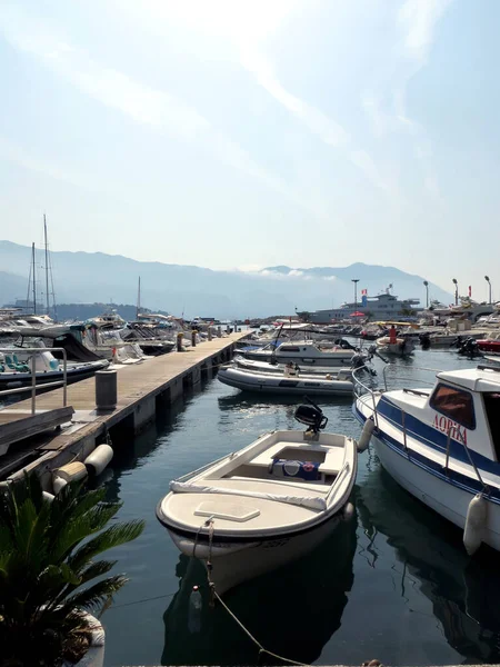 Budva / Montenegro - July 21, 2014: Motor boat and white boats are moored on the water near the pier of the city of Budva Montenegro. Silhouettes of mountains and blue