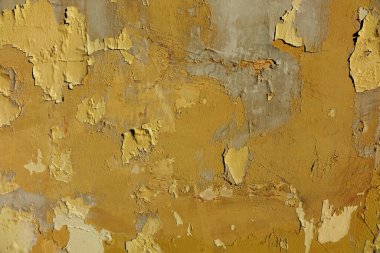 Wall with peeled bright paint, yellow orange gray plaster
