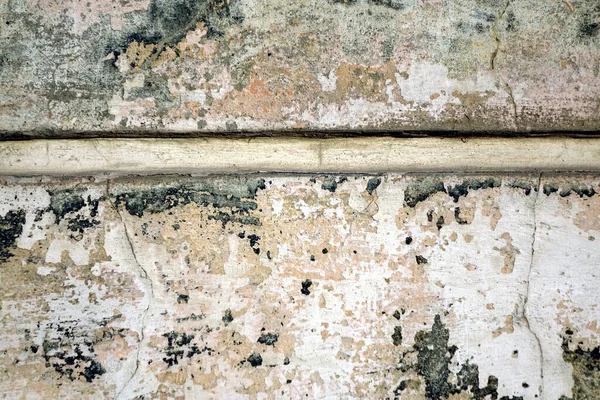 Çatlaklar ve beton duvardaki boyalar bitmiş. Beyaz noktalar, sarı ve yeşilin gölgeleri ve bitiş çizgisi.