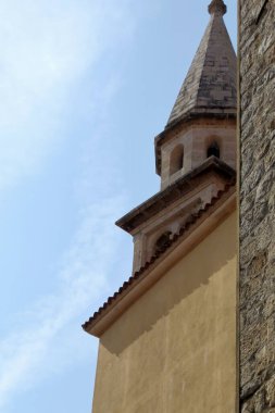 Kilisenin çan kulesi. Sarı duvarı ve binanın taş köşesi var.