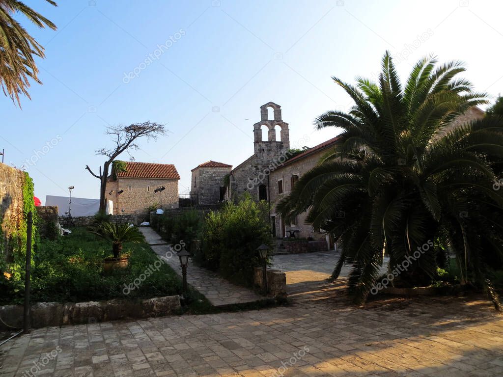 Stone church buildings with cobbled pavement and palm trees