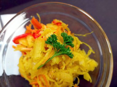 Renkli bir salatada ince dilimlenmiş lahana, tatlı biber ve bir garnitür maydanoz, parlak renkler ve temiz bir kasede taze malzemeler sergilenir..