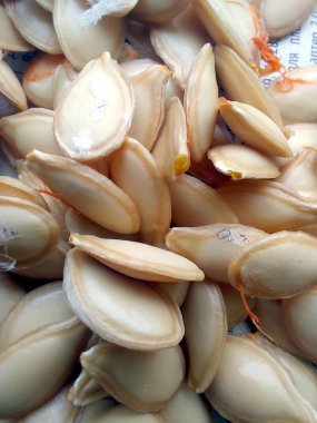 Düz bir yüzeye dizilmiş birçok balkabağı tohumunun yakın görüntüsü, kızarma ve yeme için hazırlandı. Tohumlar açık renk ve pürüzsüz bir yüzey gösteriyor.