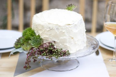 Beyaz düğün pastası yeşillik ile dekore edilmiştir..