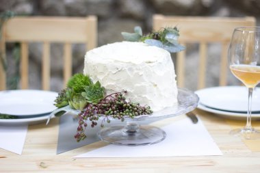Beyaz düğün pastası yeşillik ile dekore edilmiştir..