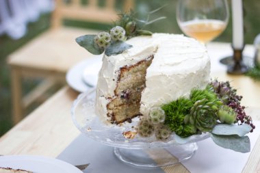 Beyaz düğün pastası yeşillik ile dekore edilmiştir..