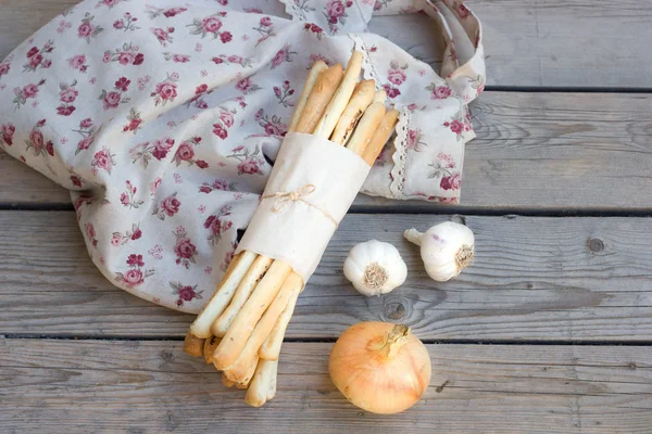 Хлебные палочки на деревянном фоне с чесноком, луком и мешками — стоковое фото