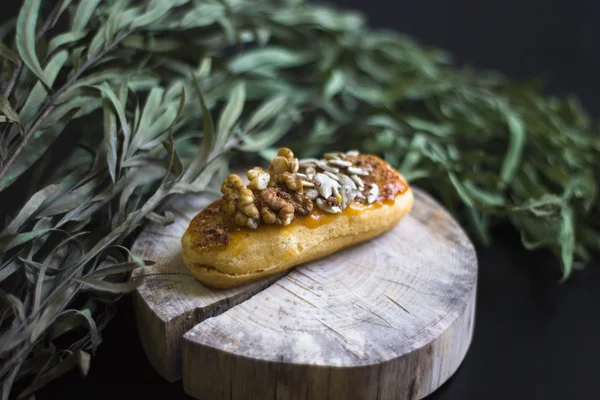 Nueces eclair en tocón de madera. sobre un fondo negro con eucalipto . — Foto de Stock