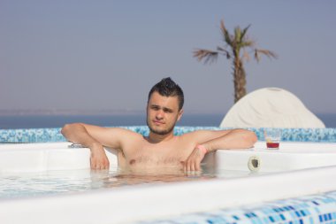 çekici bir adam havuzda bir kokteyl ile dinlenme.