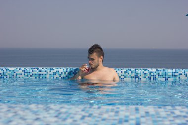 çekici bir adam bir kokteylle havuzunda yaz dinlenme.