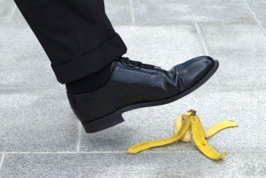 Businessman stepping on banana skin clipart