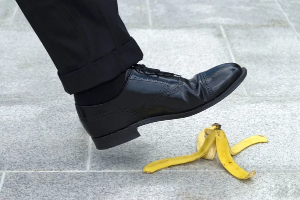 Homme d'affaires marchant sur la peau de banane Images De Stock Libres De Droits
