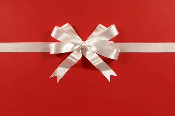 Белая подарочная лента и лук на фоне красной бумаги горизонтальный — стоковое фото