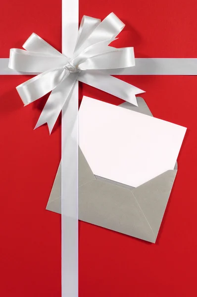 Biglietto natalizio con nastro regalo e fiocco in raso bianco su pa rosso — Foto Stock