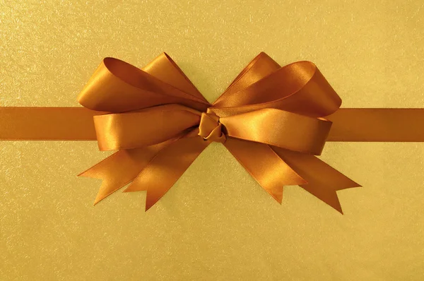 Złoty prezent łuk i Wstążka, błyszcząca folia metalowa tło papieru, — Zdjęcie stockowe