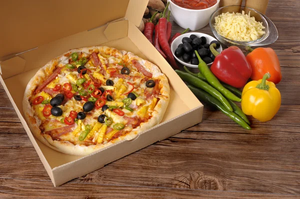 Versgebakken Pizza in levering vak met ingrediënten. — Stockfoto