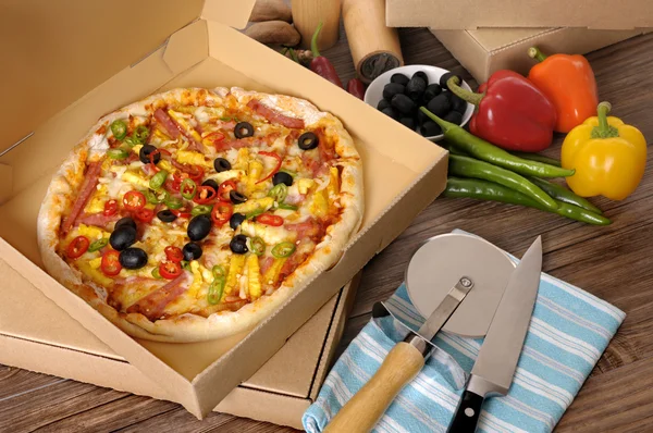 Frisch gebackene Pizza im Lieferkarton mit Zutaten. — Stockfoto