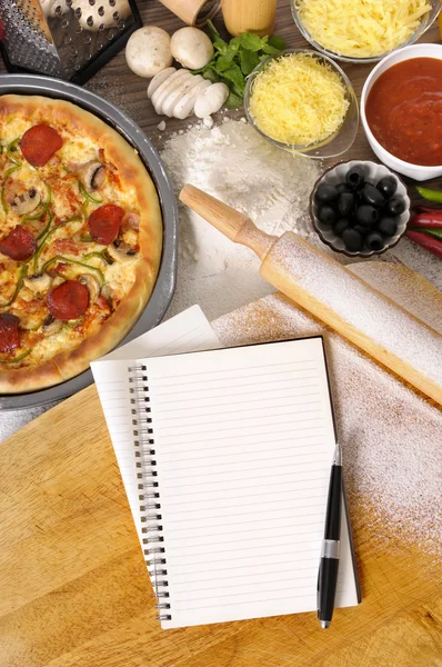 Pizza met laptop, hakken bestuur en ingrediënten — Stockfoto