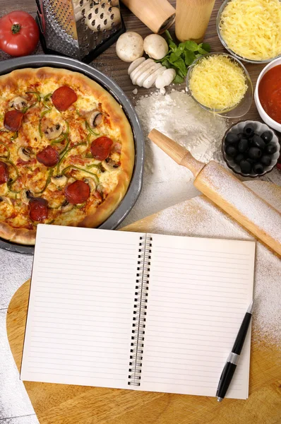 Pizza with notebook and ingredients