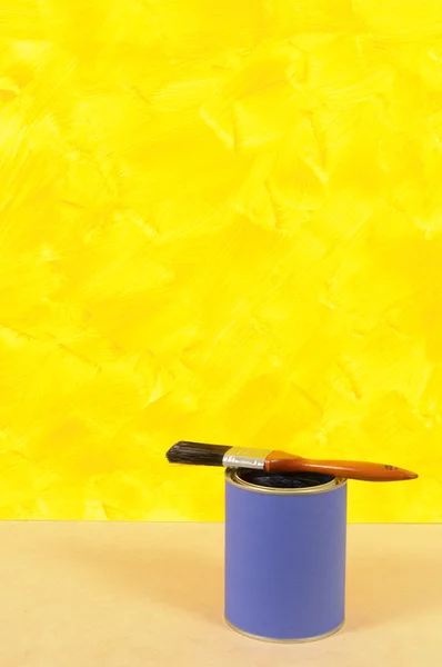 Painted yellow wall with blue paint tin — Stock Photo, Image