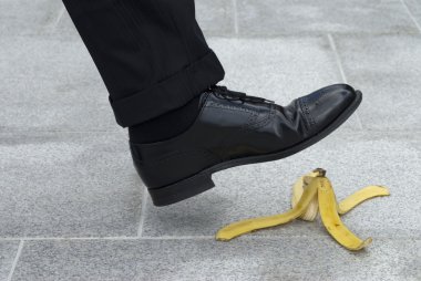 Businessman about to step on a banana skin clipart