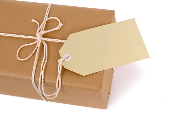 Brown paper package with white string and tag — Stock Photo, Image