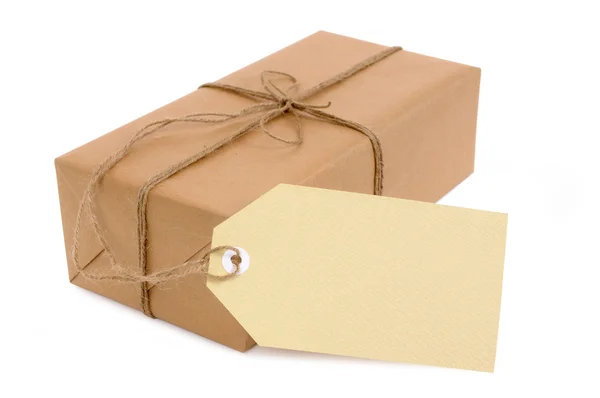 Thin brown paper package with oversize tag — Stock Photo, Image