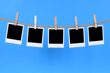 Blank instant photo prints on a washing line clipart