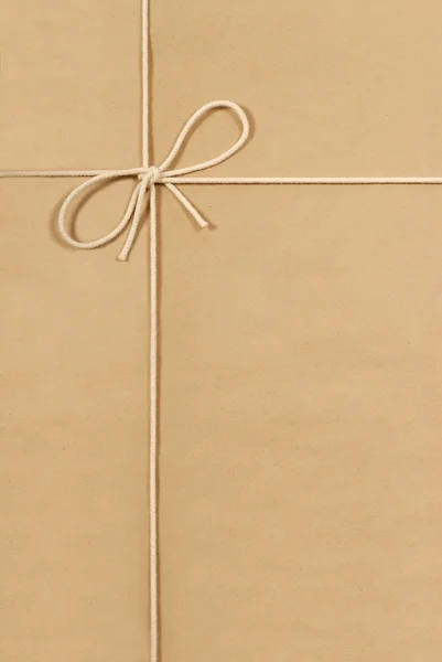 Braunes Paket mit cremefarbenem Baumwollband — Stockfoto