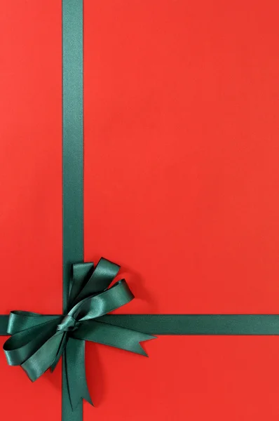 Lazo de cinta de regalo verde en papel de fondo rojo liso, espacio para copiar , —  Fotos de Stock