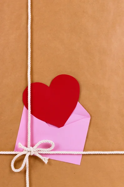 Подарунок на валентинку з червоною карткою серця або подарунковою биркою, коричневий паперовий пакет — стокове фото