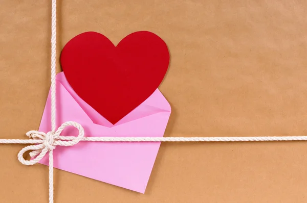 Presente Valentine com cartão de coração vermelho ou etiqueta de presente, pacote de papel marrom — Fotografia de Stock