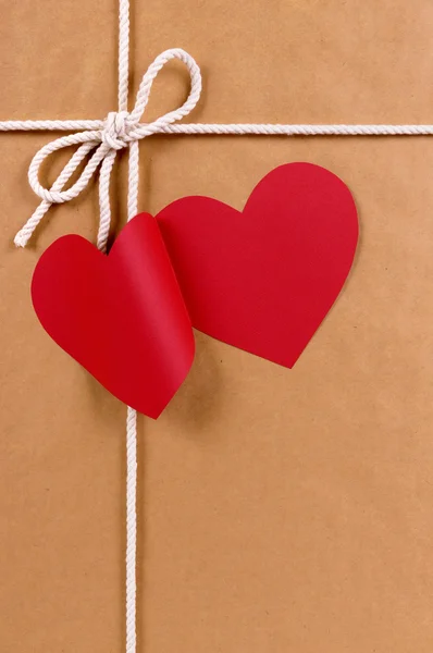 Presente do dia dos namorados com etiqueta de presente forma coração vermelho, pacote de papel marrom — Fotografia de Stock