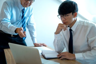 Bir iş adamı, asistanına ya da ekibine iş pazarlama operasyonunu anlatıyor. Bilgisayara işaret ediyor.