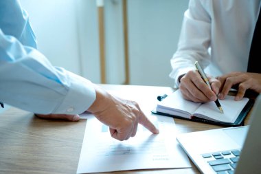 İşadamı, personel ekibine pazarlama planından bahsetmek için kağıt grafiğini işaret etti