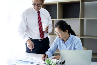 Bir işadamı danışmanı ve stajyer personel danışmanı, işletme eğitiminde koçluk yaparken grafik çizelgesini okurlar.