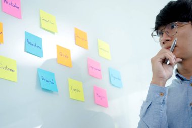 İşadamı beyaz tahtadaki not defterine bak ve elinde bir kalem tut. İş fikirlerini düşün.