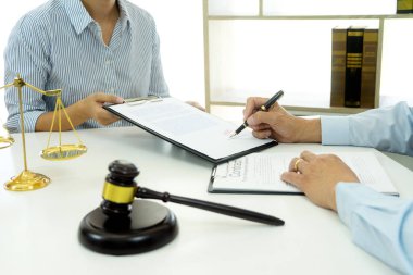 Bir hukuk firmasında, memurlar sözleşme belgelerini masaya imzalamak için avukat getirirler.