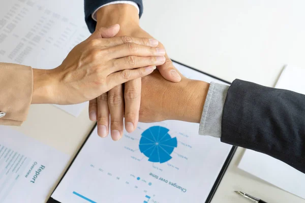 Businessmen stack their hands to show cooperation after a business deal meeting team partnership or as a congratulatory sign.