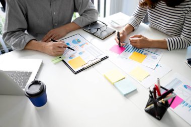 Genç iş kadını, pazarlama planlama toplantısında grafik ve grafikle birlikte yeni bir iş kurma ekibine iş planlarını anlatıyor..