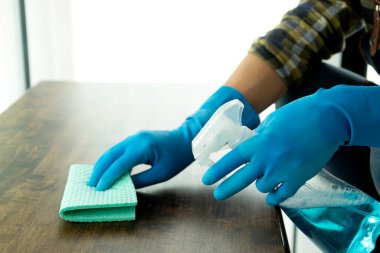 Personel, temizlik ve hastalık önleme kovid-19 için bez ve dezenfektan kullanarak masayı temizliyor..
