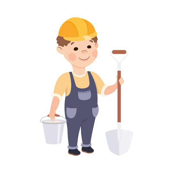 Construtor bonito com pá e balde, Menino em chapéu duro e macacão azul com ferramentas de construção Desenhos animados Estilo Vector Ilustração — Vetor de Stock